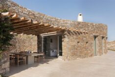 Curving stone walls allow Xerolithi vacation house to merge with Greek island landscape